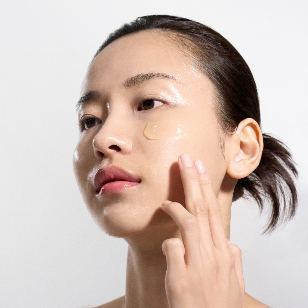Woman applying cream to her face with a white background Woman applying cream to her face with a white background