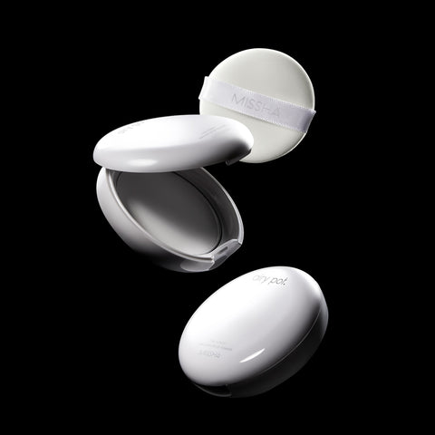 A dynamic shot of two Missha Airy Pot Pressed Powder Pact compacts and a soft white puff applicator against a black background. One compact is closed, and the other is open, displaying the interior and the MISSHA-branded powder puff, highlighting the K-beauty finishing powder and its packaging components. A dynamic shot of two Missha Airy Pot Pressed Powder Pact compacts and a soft white puff applicator against a black background. One compact is closed, and the other is open, displaying the interior and the MISSHA-branded powder puff, highlighting the K-beauty finishing powder and its packaging components.