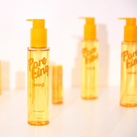 Stylized product photo of A’pieu Pore King Minji Cleansing Oil. The main yellow bottle is prominently displayed in the foreground, with multiple blurred bottles in the background. The composition and warm lighting emphasize the product’s golden hue and sleek packaging design. Stylized product photo of A’pieu Pore King Minji Cleansing Oil. The main yellow bottle is prominently displayed in the foreground, with multiple blurred bottles in the background. The composition and warm lighting emphasize the product’s golden hue and sleek packaging design.