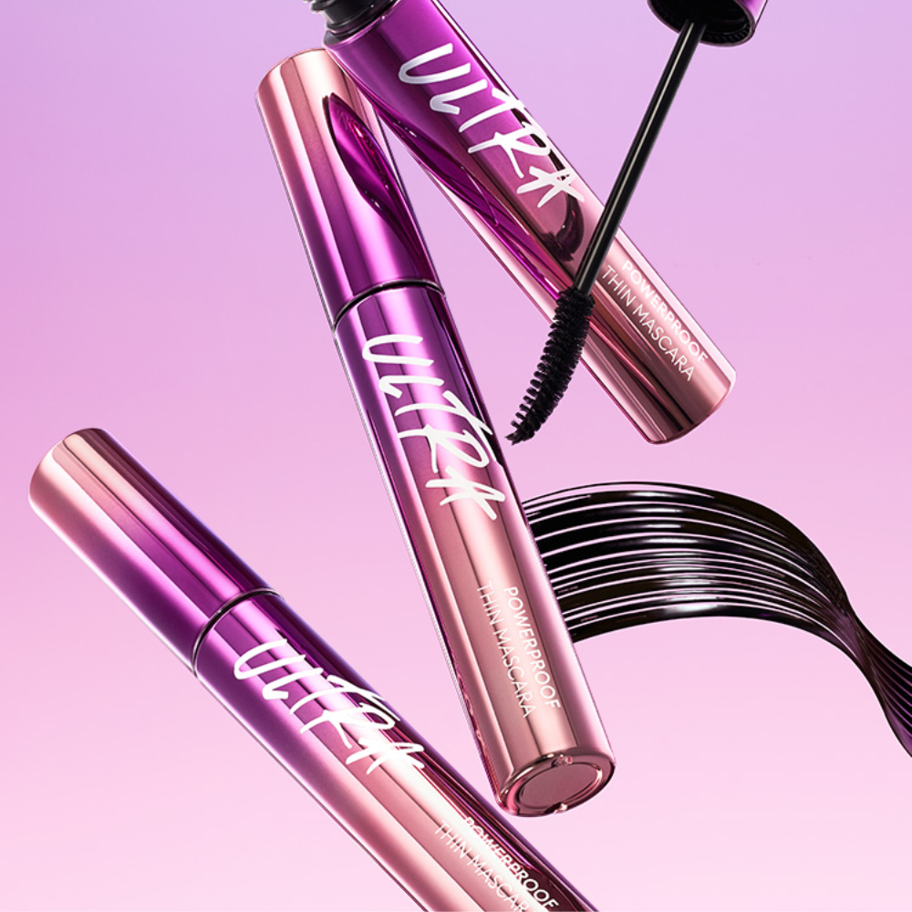 A tube of MISSHA Ultra Powerproof Thin Mascara with a brush, displayed on a reflective surface with a colorful, holographic background. A tube of MISSHA Ultra Powerproof Thin Mascara with a brush, displayed on a reflective surface with a colorful, holographic background.