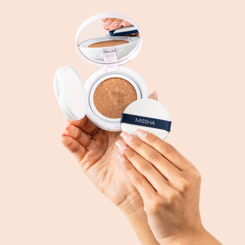 Stylized shot of model hand holding compact and cushion applicator Stylized shot of model hand holding compact and cushion applicator