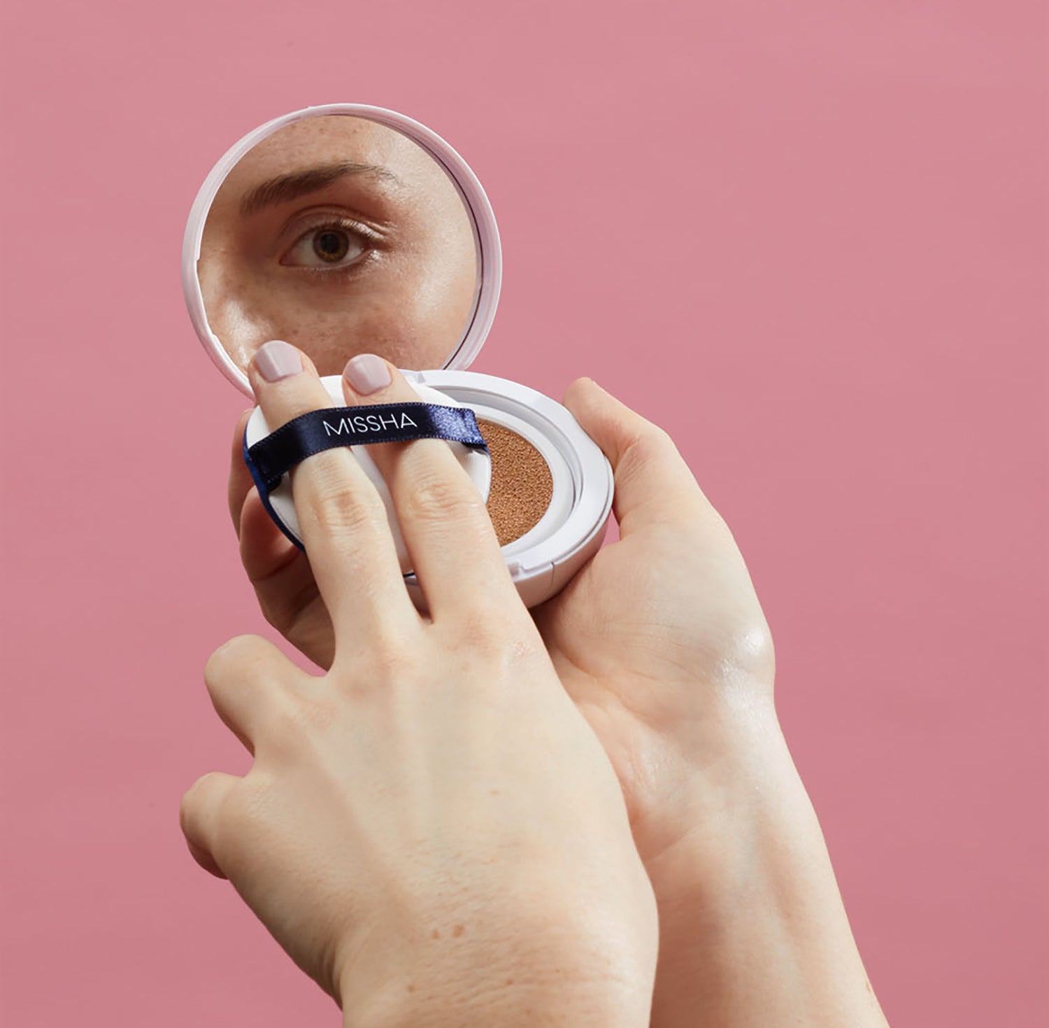 Model looking a cushion compact mirror Model looking a cushion compact mirror