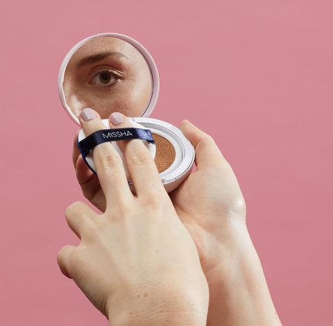 Model looking a cushion compact mirror Model looking a cushion compact mirror