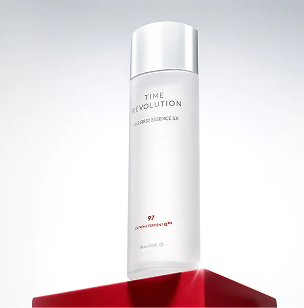 Sleek white Time Revolution The First Essence SX bottle displayed on a bold red pedestal, highlighting premium skincare.