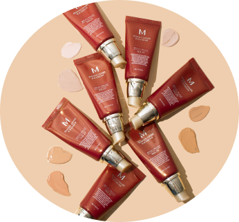 Eight red skincare tubes with golden caps arranged in a circle, surrounded by cream drops on a beige background.
