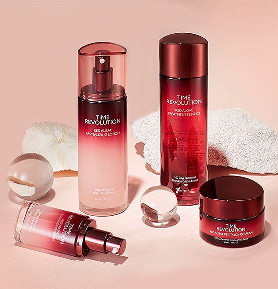 Four Time Revolution skincare products with red algae, artfully arranged on a soft pink background with coral accents.