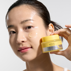 Woman applying cream to her face with a jar of VITA C cream in front of her.