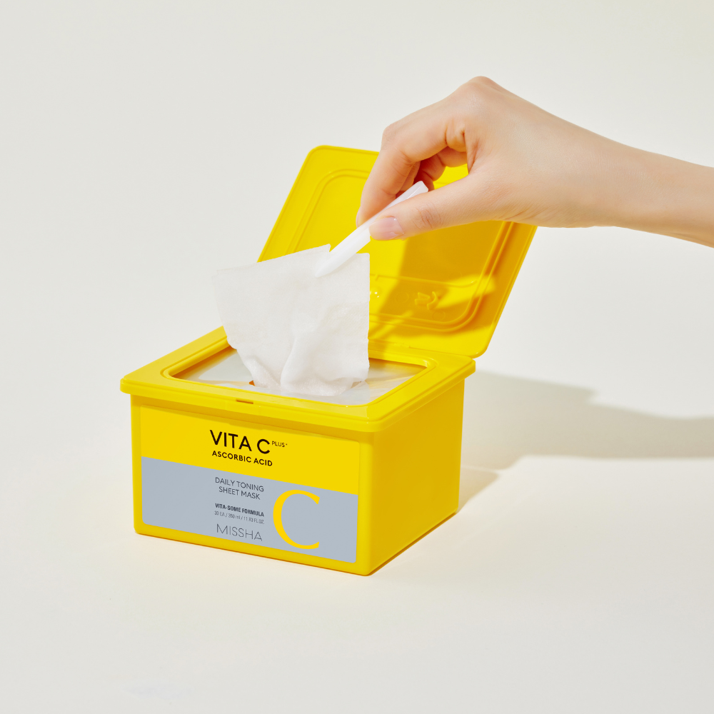 Yellow container of VITA C facial wipes with a hand taking a wipe out on a light background
