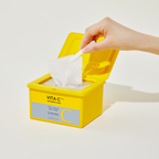 Yellow container of VITA C facial wipes with a hand taking a wipe out on a light background