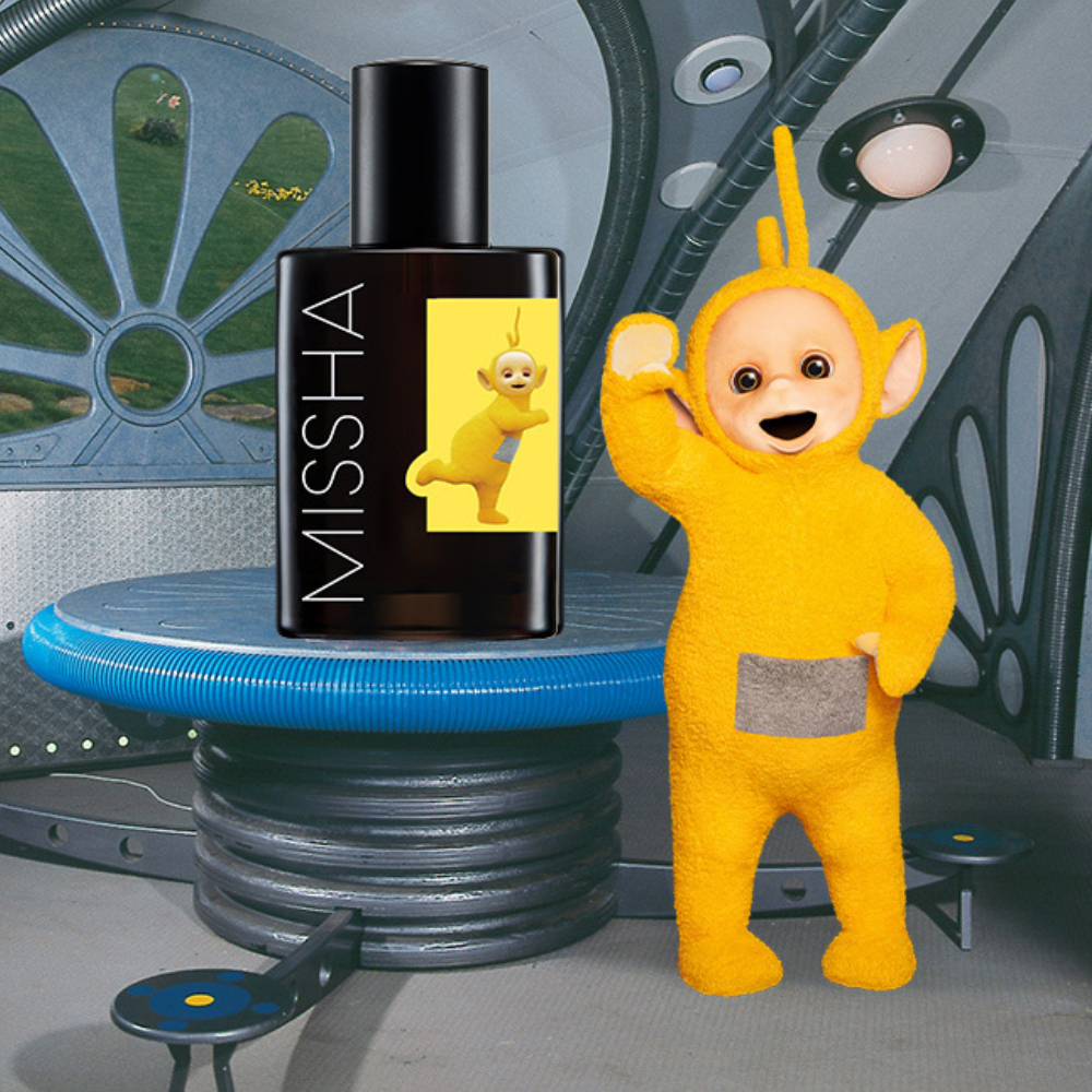 MISSHA Teletubbies edition ampoule bottle featuring the yellow Teletubby on the label, displayed indoors beside the matching Teletubbies character waving.