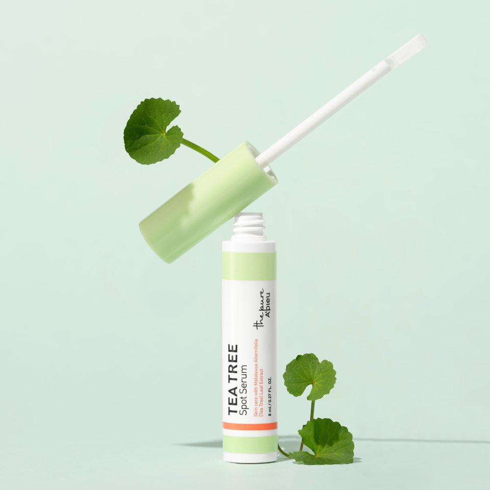 Tea tree skin serum bottle with green leaves on a light green background