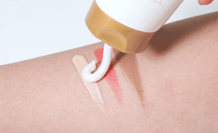 A close-up of a hand gently applying a white cream onto the skin, showing the smooth texture and absorption of the product.