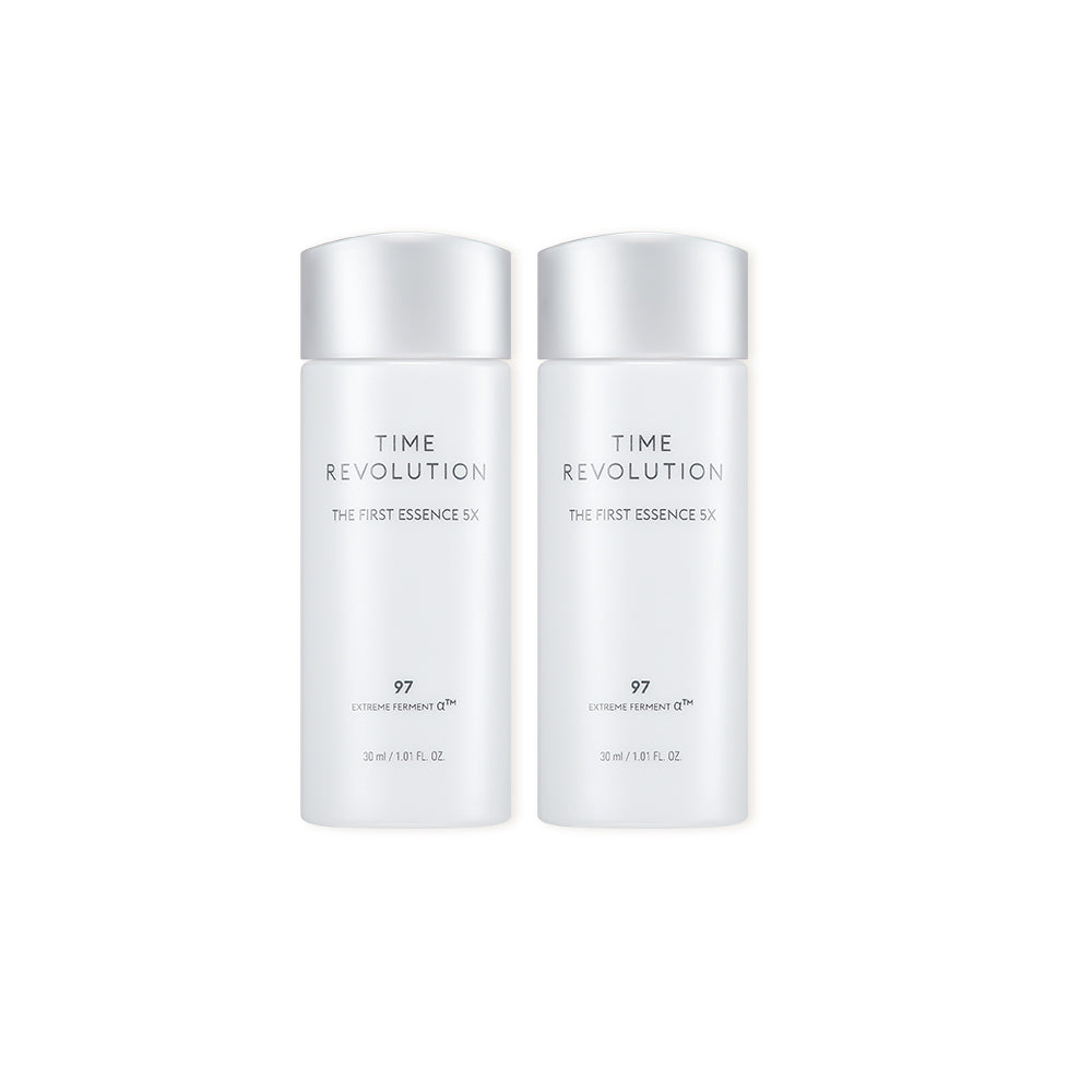 Two small, white bottles of Time Revolution The First Essence 5X. This rejuvenating K-beauty essence is part of the Prime Stem 100 Gift Set and is used to hydrate and prep skin before applying the lifting serum and cream.