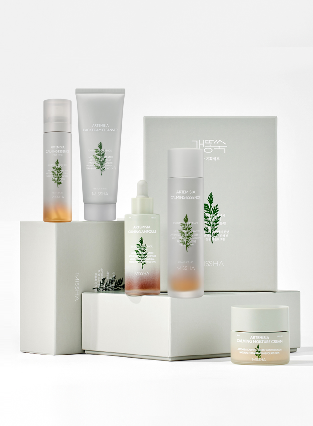 Skincare collection with calming essence, foam cleanser, ampoule, and moisturizer, elegantly arranged on white boxes.