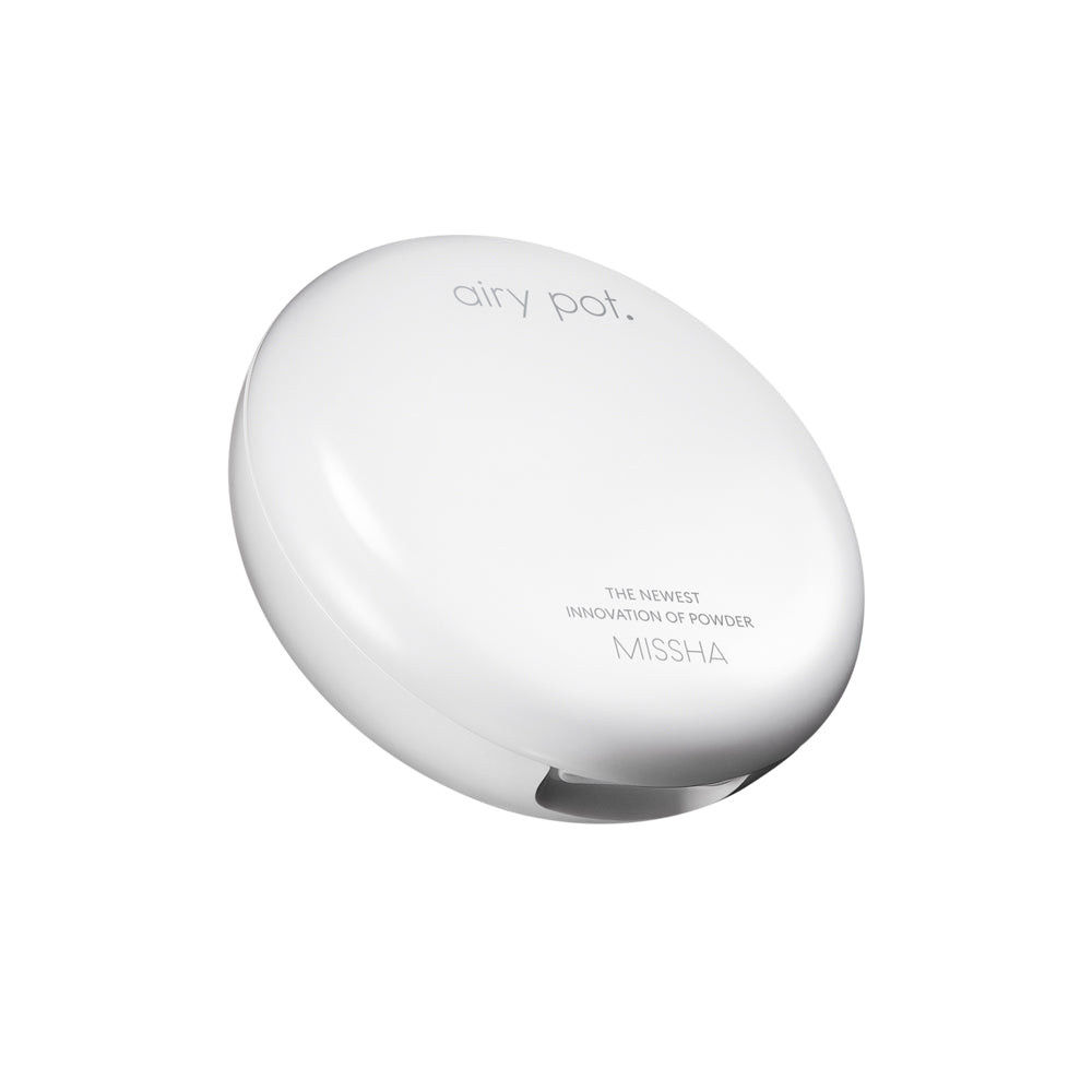 Angled view of the closed, white, minimalist compact packaging for the Missha Airy Pot Pressed Powder Pact. The packaging displays the product name 'airy pot' and 'MISSHA', showcasing the sleek K-beauty setting powder compact design.