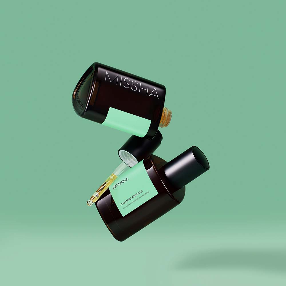 A black and green bottle of Missha Time Revolution Artemisia Ampoule with a dropper, set against a green background.