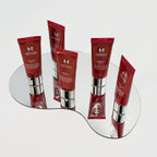 Multiple tubes of MISSHA M Perfect Cover BB Cream standing on an irregularly shaped mirror, reflecting their red packaging with silver caps.