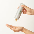 A person pours MISSHA Artemisia Calming Essence into their palm, showing the product’s lightweight, watery texture suitable for soothing and hydrating the skin.