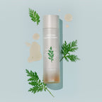 MISSHA Artemisia Calming Essence bottle placed on a light blue background with drops of essence and sprigs of Artemisia leaves, highlighting its soothing, herb-based formulation and lightweight texture.