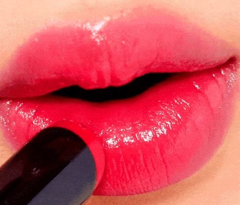 Close-up of glossy pink lips being applied with a lipstick or lip balm, showing a smooth and shiny finish that enhances lip color and hydration.