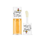 A'pieu Honey & Milk Lip Oil in a clear tube with orange-colored product visible inside. The packaging is adorned with illustrations of honeycomb and the product is equipped with a white applicator.