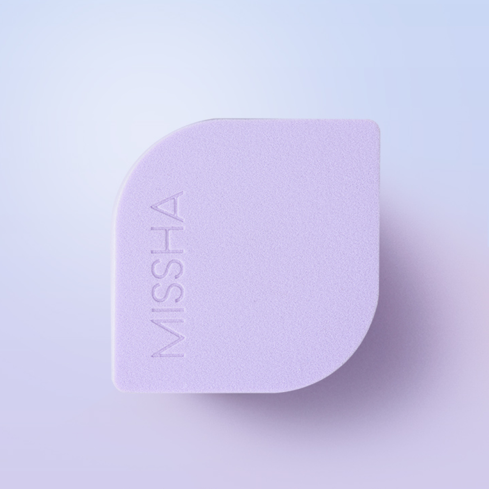 Top and front view of the MISSHA Layering Fit Puff, showing its unique shape with a pointed tip for precision and a flat surface for blending. The MISSHA logo is visible on the product.