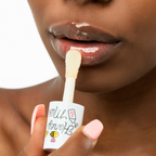 Close-up of a Black model applying the A'pieu Honey & Milk Lip Oil using the oversized doe-foot applicator, which leaves a high-shine, glossy finish on the lips, emphasizing deep moisturizing and plumpness.