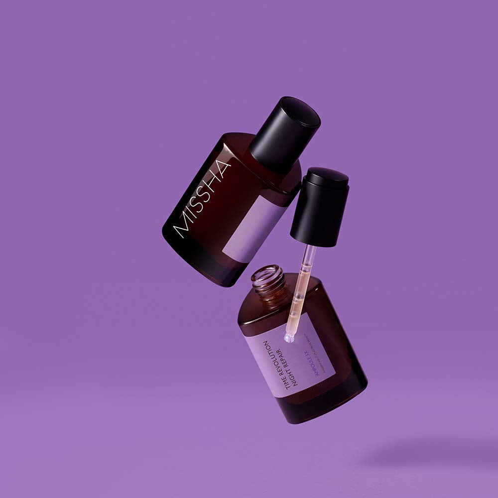 Two bottles of Missha Time Revolution Night Repair Ampoule 5X suspended in the air against a purple background, one with the dropper outstretched.