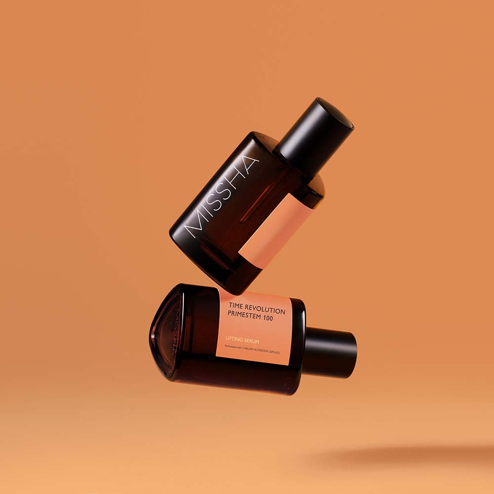 Two bottles of MISSHA skin care serum levitating against a beige background, with one bottle cap off showing the product name 'TIME REVOLUTION PRIMESTEM 100 LIFTING SERUM'.