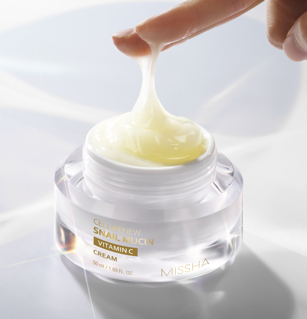 Extreme close-up of a finger lifting the Missha Cell Renew Snail Mucin Vitamin C Cream from the jar, demonstrating the thick, stringy, and highly viscous texture of the anti-aging moisturizing cream.