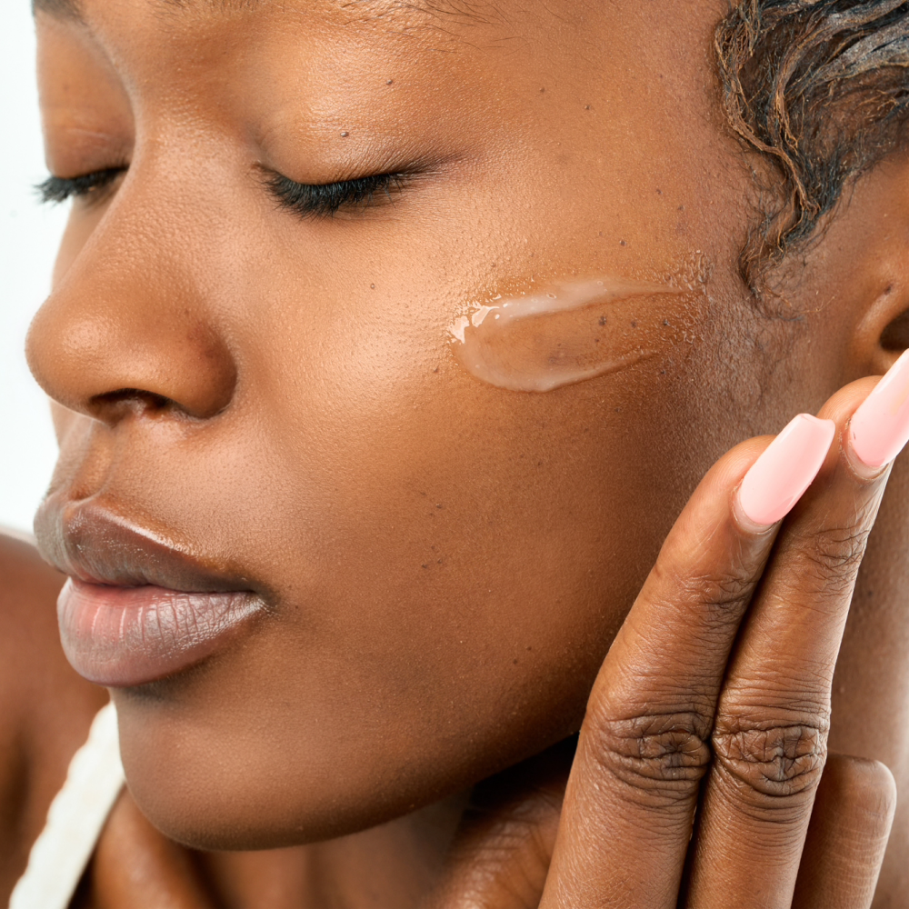 Close-up of a Black model applying the Missha Cell Renew Snail Mucin Vitamin C Cream to her cheek, showing the product's gel-like, moisturizing finish on the skin.