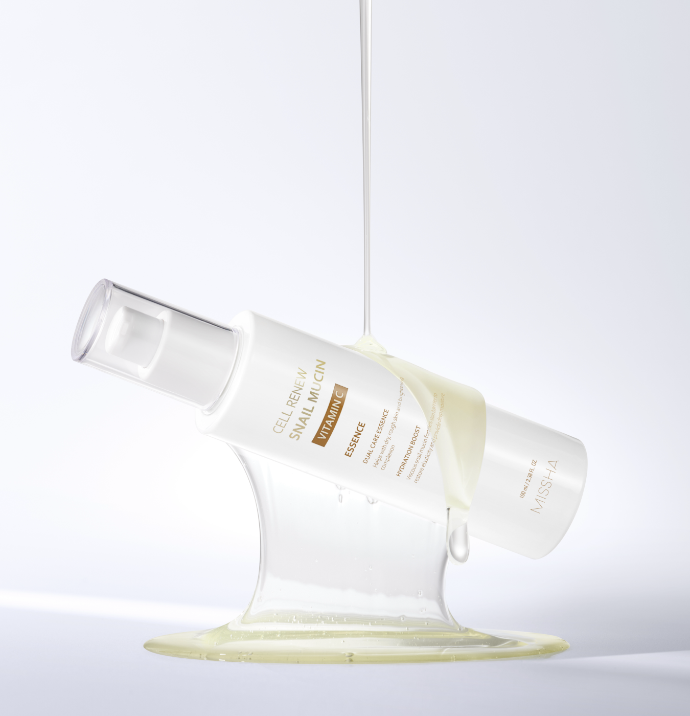 Studio shot of the Missha Cell Renew Snail Mucin Vitamin C Essence bottle tilted, held up by a visible stream of the thick, viscous serum that highlights the snail mucin ingredient's texture for intense skin repair and anti-aging.