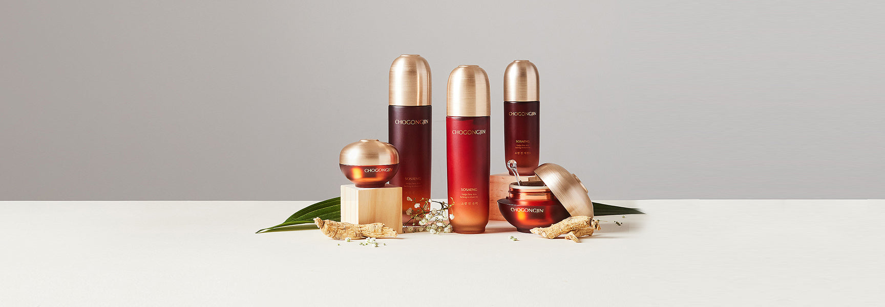 Skincare products in elegant jars and bottles with gold accents, styled with natural elements on a neutral backdrop.