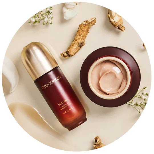 A bottle and jar of Chogongjin skincare products on a beige surface, surrounded by herbs and delicate white flowers.