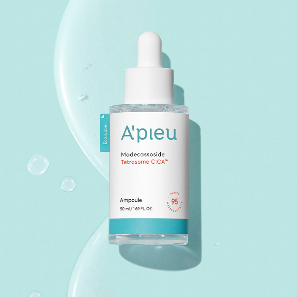 Studio shot of the A'pieu Madecassoside Tetrasome Cica Ampoule dropper bottle standing against a clear light blue background. Large droplets of the soothing serum surround the bottle, emphasizing its calming and skin barrier repair benefits.