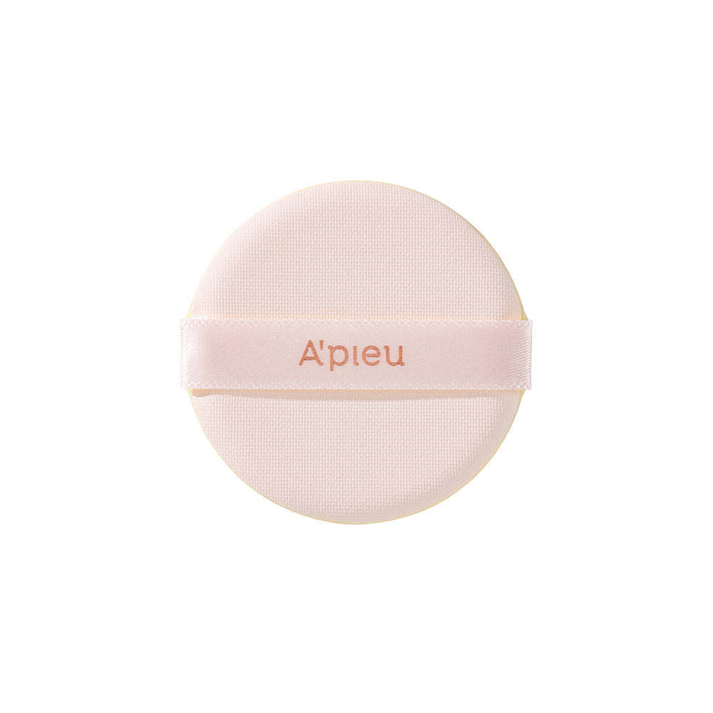 Close-up of the round, soft application puff for the A'pieu Cushion Foundation, featuring the 'A'pieu' logo on the light pink ribbon strap.