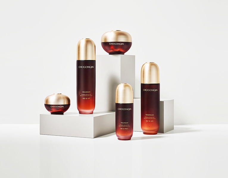 An artistic display of five skincare bottles with gold caps on white pedestals, showcasing luxury and elegance.