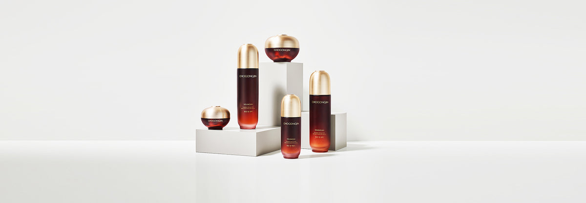 An artistic display of five skincare bottles with gold caps on white pedestals, showcasing luxury and elegance.
