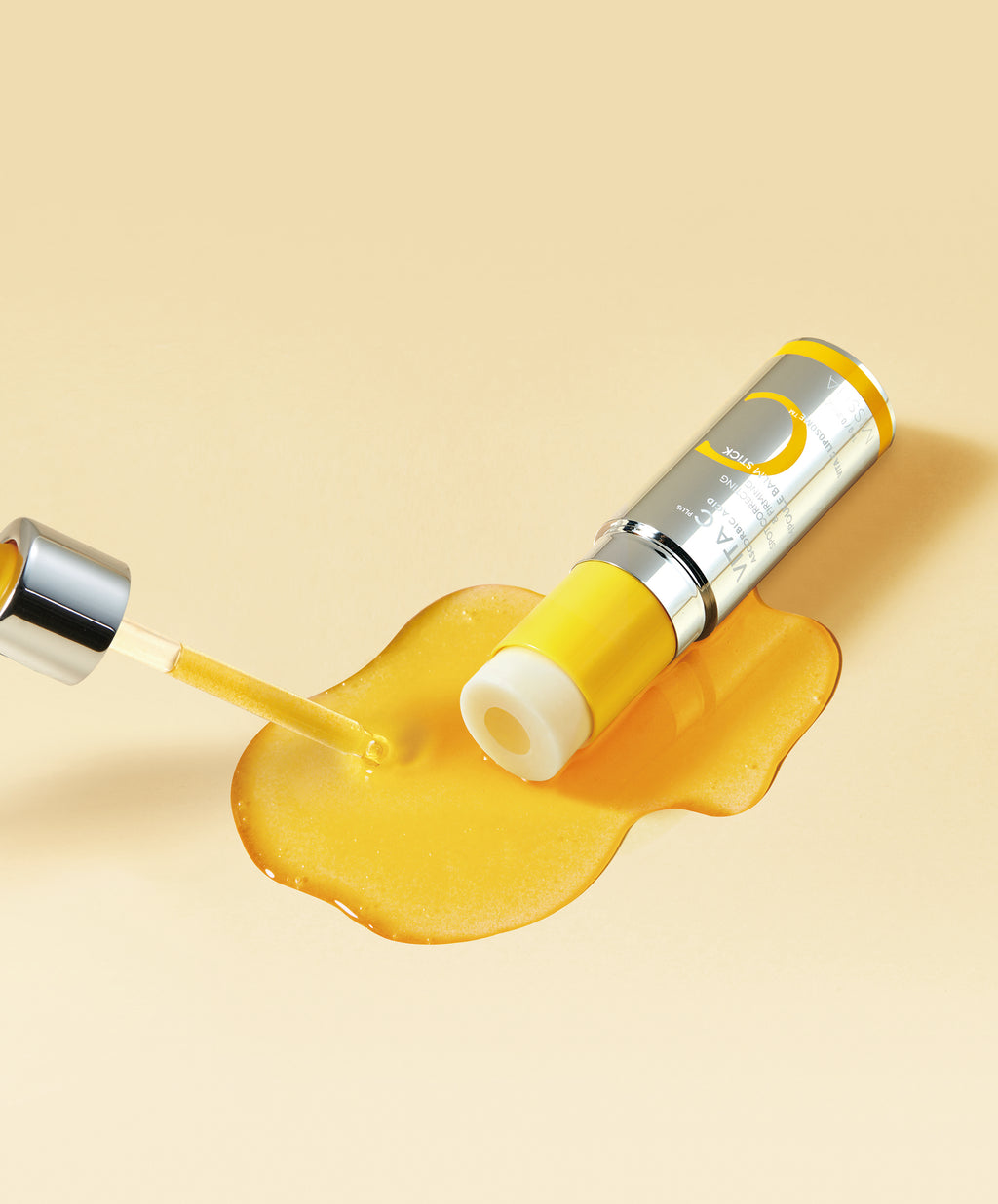Close-up of the yellow, exposed balm of the Missha Vita C Plus Spot Correcting & Firming Ampoule Balm Stick resting in a puddle of serum-like liquid, next to a dropper. This highlights the concentrated VITA C DOUBLE COATING TECHNOLOGY formula for dark spots and firming.