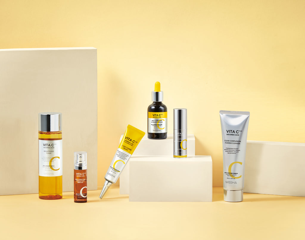 A display of the full Missha Vita C Plus line, including the Toner, Ampoule, Eraser Toning Cream, and the new Spot Correcting & Firming Ampoule Balm Stick. This shows the complete Vitamin C-rich routine for tackling dark spots and dullness.