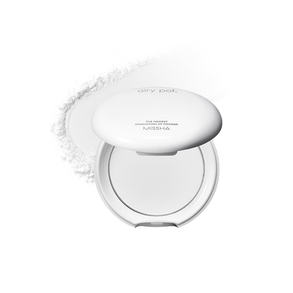 Missha Airy Pot. A compact white powder pact with a pressed powder formula, displayed against a white background. With a white trail of powder behind.