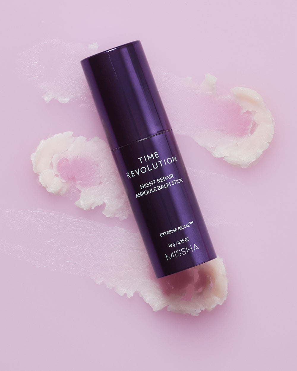 MISSHA Time Revolution Night Repair Ampoule Balm Stick with Extreme Biome™ formula shown on textured pink background, highlighting its melting dual-balm texture for firming and wrinkle care