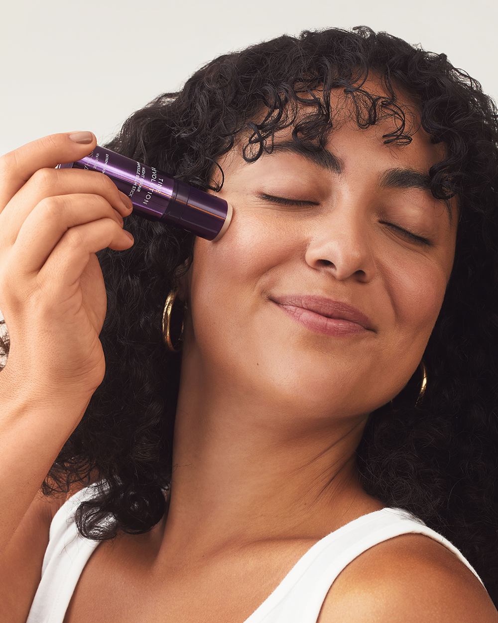 Model applying MISSHA Time Revolution Night Repair Ampoule Balm Stick on cheek, showing easy on-the-go wrinkle care and firming skincare routine