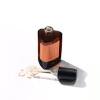 A dark amber, triangular bottle of the Missha Time Revolution Primestem 100 Lifting Serum with the cap off, lying on its side next to a spill of the serum. The image emphasizes the unique packaging and rich liquid texture of the Primestem 100 anti-wrinkle serum.